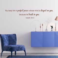 a blue chair sitting in front of a wall with a bible verse written on it