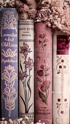 four books are lined up next to each other with flowers on the covers and in front