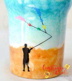 a painted cup with a man holding a kite