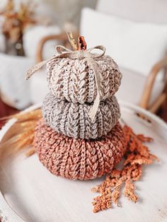 three knitted pumpkins sitting on top of a white plate