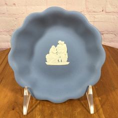 a blue plate sitting on top of a wooden table next to a brick wall,