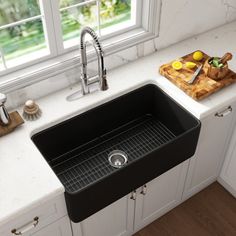 a black kitchen sink sitting on top of a counter next to a wooden cutting board