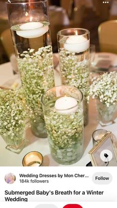 three tall vases filled with baby's breath flowers and candles on a table