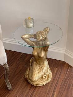 a glass table topped with a gold mermaid statue