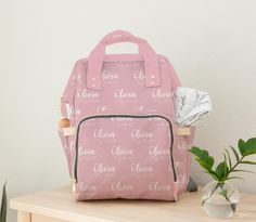 a pink backpack sitting on top of a wooden table next to a potted plant