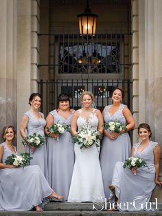 a group of women standing next to each other in front of a building holding bouquets