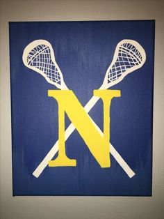 two lacrosse sticks and the letter n painted on a canvas