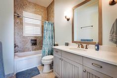 a bathroom with a sink, toilet and bathtub next to a shower curtained window