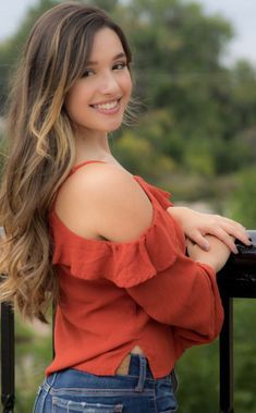 a beautiful young woman standing next to a railing