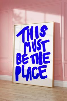 this must be the place poster in front of a pink wall with blue writing on it