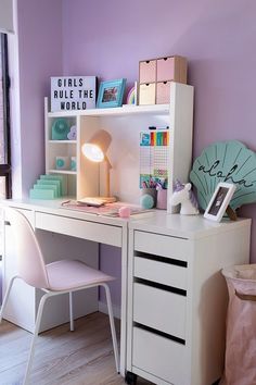 a white desk and chair in a room with purple walls, bookshelves and other items