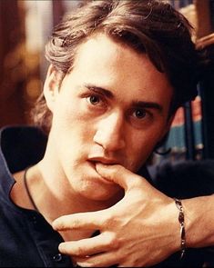 a close up of a person with a watch on his wrist and books in the background