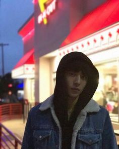 a man standing in front of a mcdonald's with his hood pulled up and looking at the camera