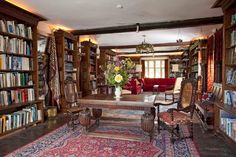 a room with lots of bookshelves and chairs in the center, along with a rug on the floor