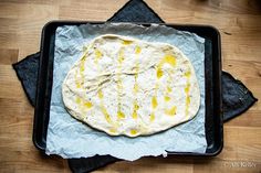 an uncooked pita bread sitting on top of a pan covered in melted cheese