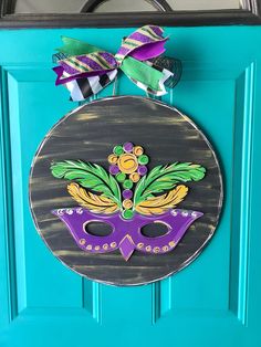 a blue door with a purple mask and green leaves on the front, hanging from it's side