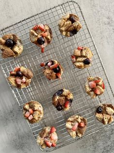 several pastries on a cooling rack with strawberries and blueberries in the middle