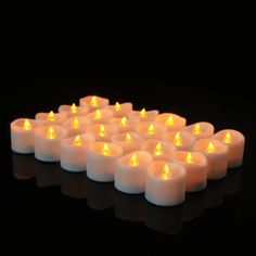 many lit candles are arranged in the shape of a heart on a black surface with reflections