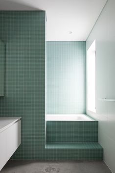 an empty bathroom with green tiled walls and floor