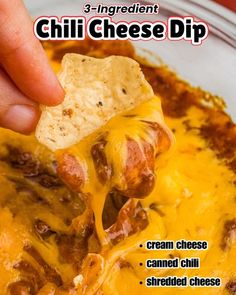 a hand holding a tortilla chip over a bowl of chili cheese dip with the recipe in it