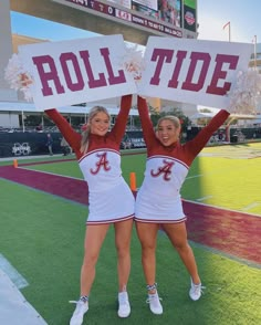 two cheerleaders holding up their signs at a football game