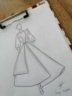 a drawing of a woman's dress on a piece of paper next to a pen