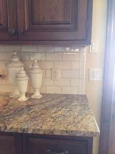 two white vases sitting on top of a counter in a kitchen next to cabinets