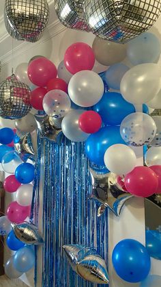 balloons, streamers and disco balls are hanging from the ceiling in this party room