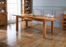 a wooden table sitting on top of a hard wood floor next to a book shelf