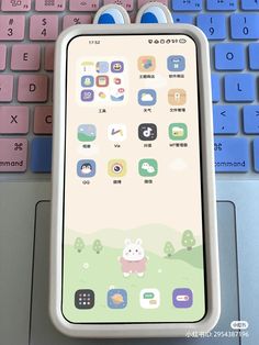 an iphone sitting on top of a laptop keyboard next to a pink and blue keyboard