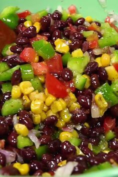 a green bowl filled with black beans and corn