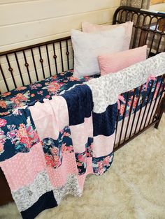 a baby crib with pink and blue quilts on it's bedding