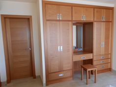 an empty room with wooden cabinets and drawers on the wall, including a dressing table