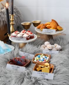 a table topped with cakes and cupcakes on top of a fur covered floor