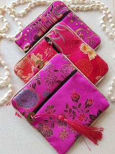 Gorgeous Chinese Brocade fabric Jewelry and Gift pouches. These stunning pouches and are wonderful for storing your jewelry and are perfect to give as a gift. There is a choice of three beautiful pink shades for you to choose from, each pouch has a zipper, lined inside and has a tassel. Why not add one of these lux pouches to your order.  The Pouches are approximately 12cm x 12cm. Pink Foldable Rectangular Bag, Portable Pink Rectangular Cosmetic Bag, Pink Rectangular Pouch, Handmade Pink Cosmetic Bag For Travel, Pink Rectangular Coin Purse For Travel, Pink Coin Purse With Removable Pouch, Handmade Pink Bag For Personal Use, Rectangular Pink Pouch For Personal Use, Pink Pouch Wallets For Personal Use