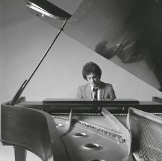 a man sitting at a piano in front of a painting