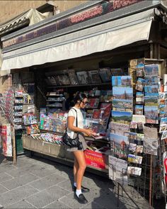 a woman walking past a store selling magazines