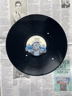 an old record is on display in front of a newspaper page with the image of a robot