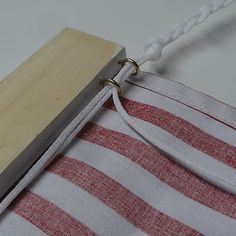 a piece of wood is attached to a red and white striped material with a metal hook