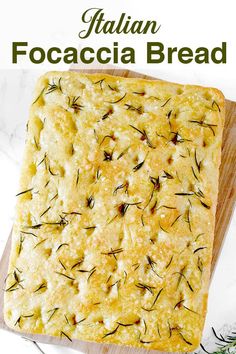 an image of italian focaccia bread on a cutting board with rosemary sprigs