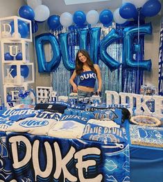 a woman standing in front of a bed covered in blue and white decorations with balloons