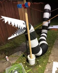 an upside down trash can sitting in the grass next to a pole with a shark on it