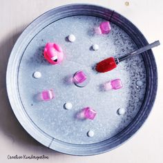 a bowl filled with ice cubes and pink marshmallows next to a spoon