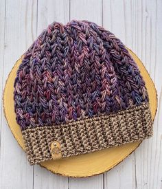 a knitted hat sitting on top of a wooden table next to a yellow plate