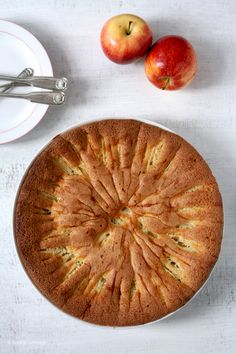 an apple cake on a plate next to two apples