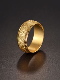 a gold wedding ring on a black surface