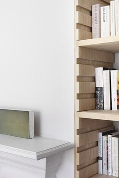 a bookshelf filled with lots of books next to a white wall