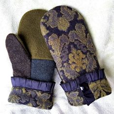 two oven mitts sitting on top of a white sheet covered in purple and gold flowers