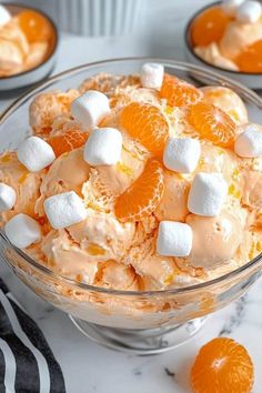 a bowl filled with oranges and marshmallows on top of a table