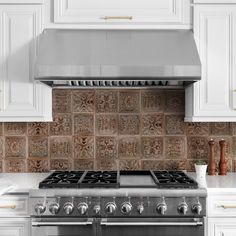 a stove top oven sitting inside of a kitchen next to white cupboards and drawers